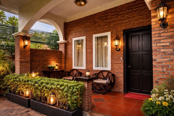 A brick exterior with a black door, two windows, and outdoor seating with lanterns. - Kravan Siem Reap Boutique Villa (Siem Reap)