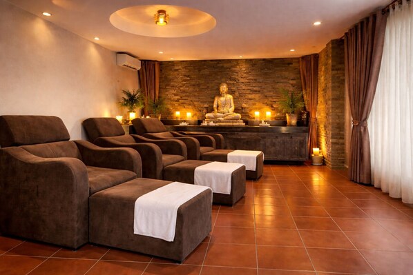 A spa room with multiple massage chairs, a Buddha statue, and a stone wall. - Kravan Siem Reap Boutique Villa (Siem Reap)