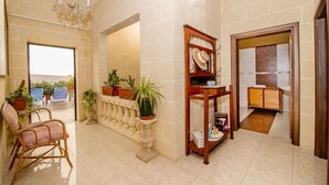 A spacious living area with a balcony, a wooden shelf with decorative items, and a view of the outside. - Ta Joseph (Xewkija)