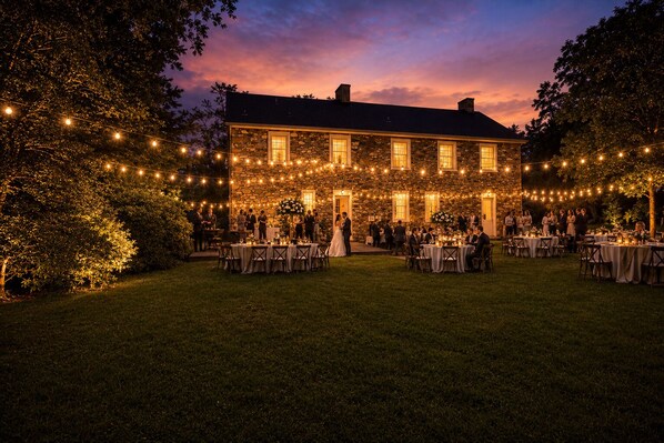 A stone building with multiple tables and chairs set up for an event.