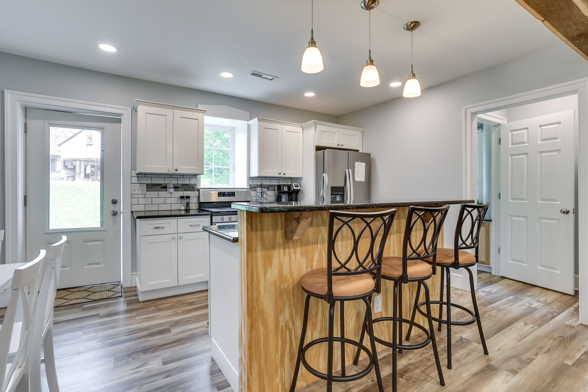 Kitchen with white cabinets, breakfast bar seating, and stainless steel appliances.