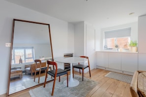 A modern kitchen with white cabinetry, a round dining table, and a large mirror. - Chic 1BDR City Retreat with Views of the Shard (Greater London)