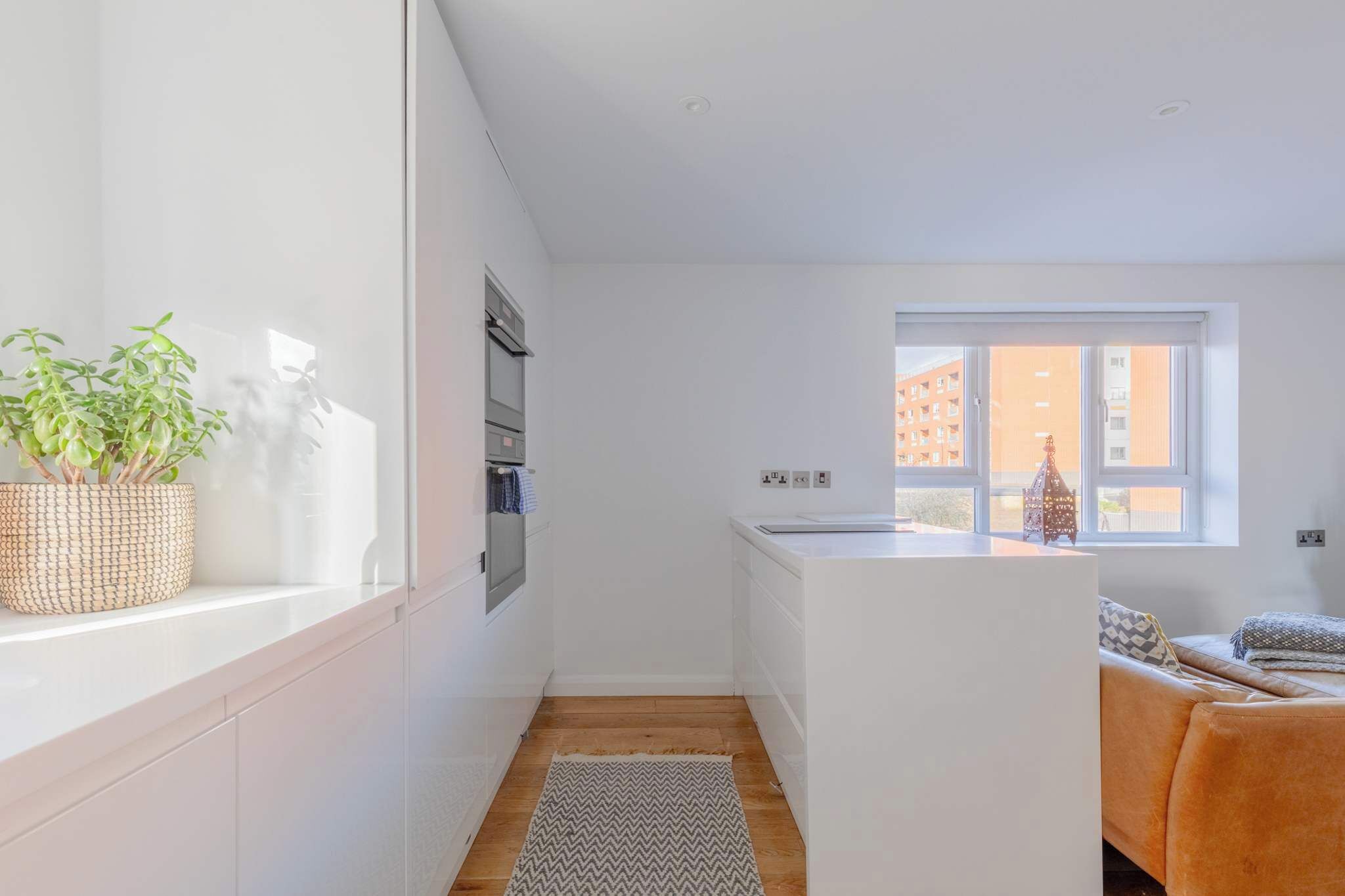 Une cuisine moderne avec des meubles blancs, une fenêtre et un petit îlot central.