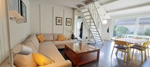 A living room with a sofa, coffee table, and a dining area with chairs and a table. - De Haerde 27, quiet vacation park near the North Sea beach (Ellemeet)