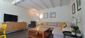 A modern living room with a sofa, a coffee table, a TV, a chair, and a cabinet. - De Haerde 27, quiet vacation park near the North Sea beach (Ellemeet)