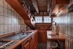 Uma cozinha com armários de madeira, um fogão e uma janela com cortinas de renda.