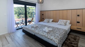 Une chambre dotée d’un grand lit, d’une tête de lit en bois et donnant sur une terrasse aménagée avec du mobilier d’extérieur.