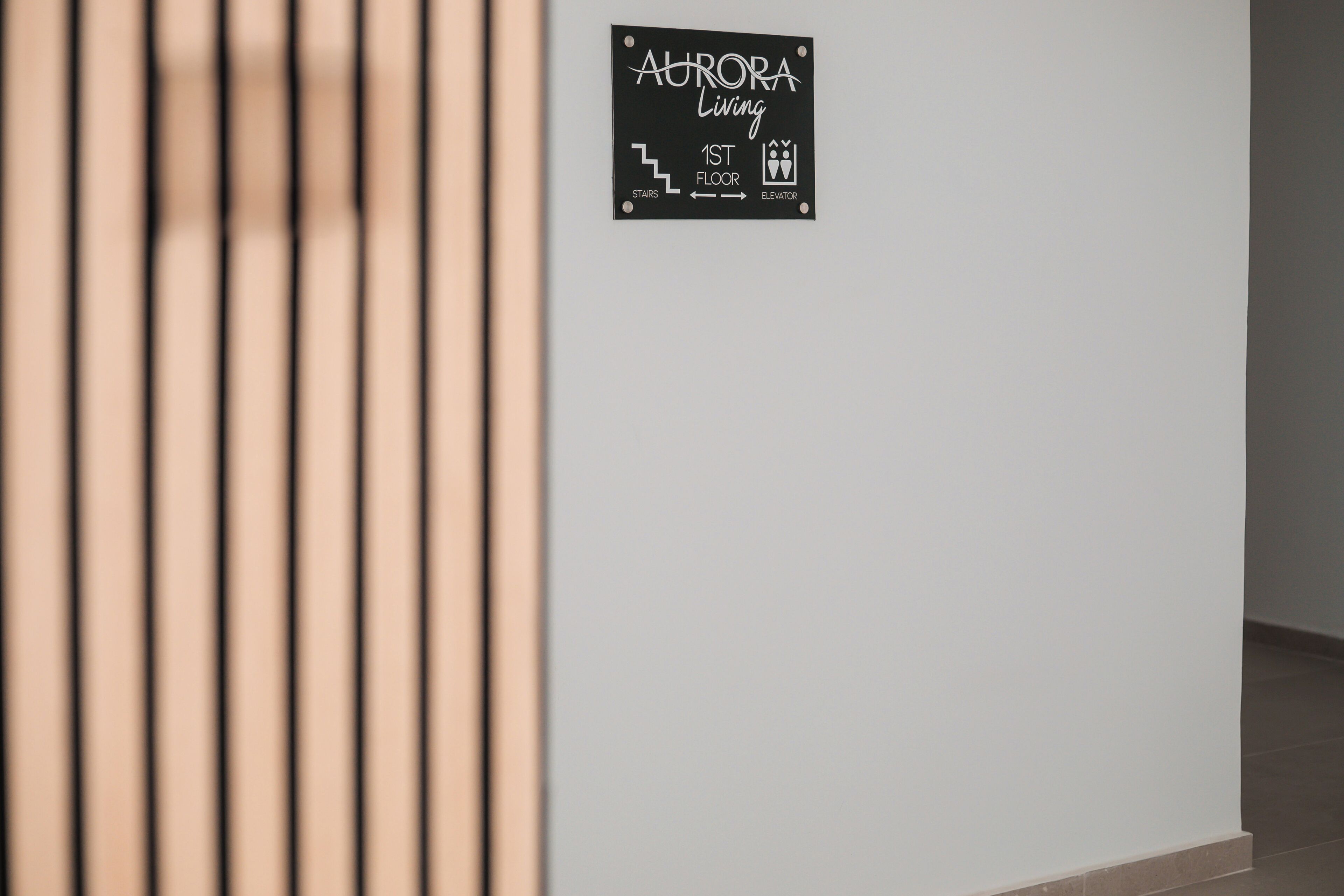 A sign indicating the location of the 1st floor and elevator in a building named Aurora Living.