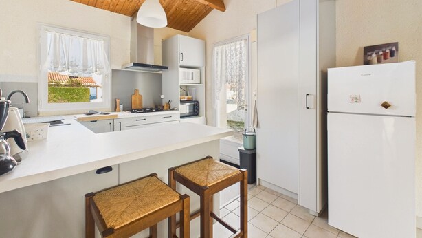 Una cocina moderna con armarios blancos, techo de madera y un ventanal grande.