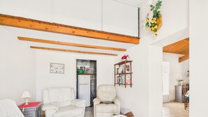 Una sala de estar con sofá, dos sillones, una mesa de centro de madera y una estantería.