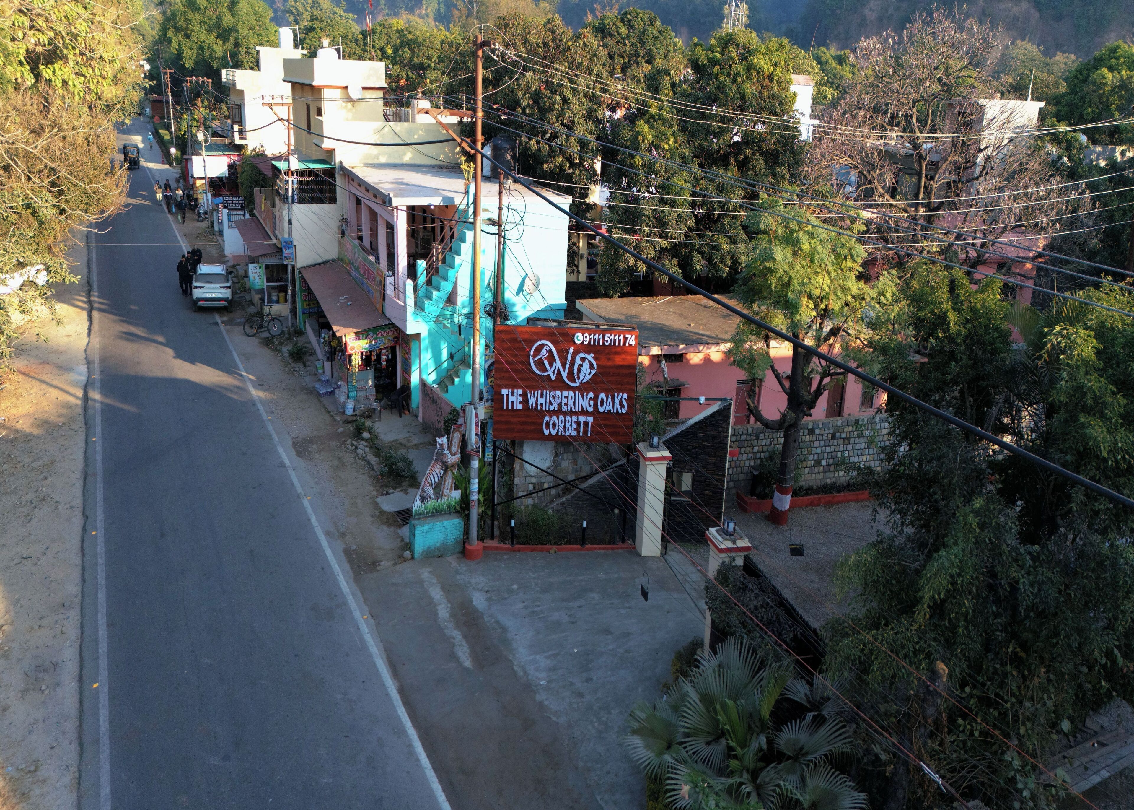 Vista callejera con un cartel que indica 'The Whispering Oaks Corbett' hotel.