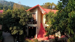 A two-story building with a red roof and a balcony on the upper floor. - The Whispering Oaks Corbett (Ramnagar)