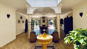 A spacious indoor area with a central fountain, patterned floor tiles, and a high ceiling with a skylight. - Riad Sahara Experience • Swimming pool (Souss-Massa Belfaa)
