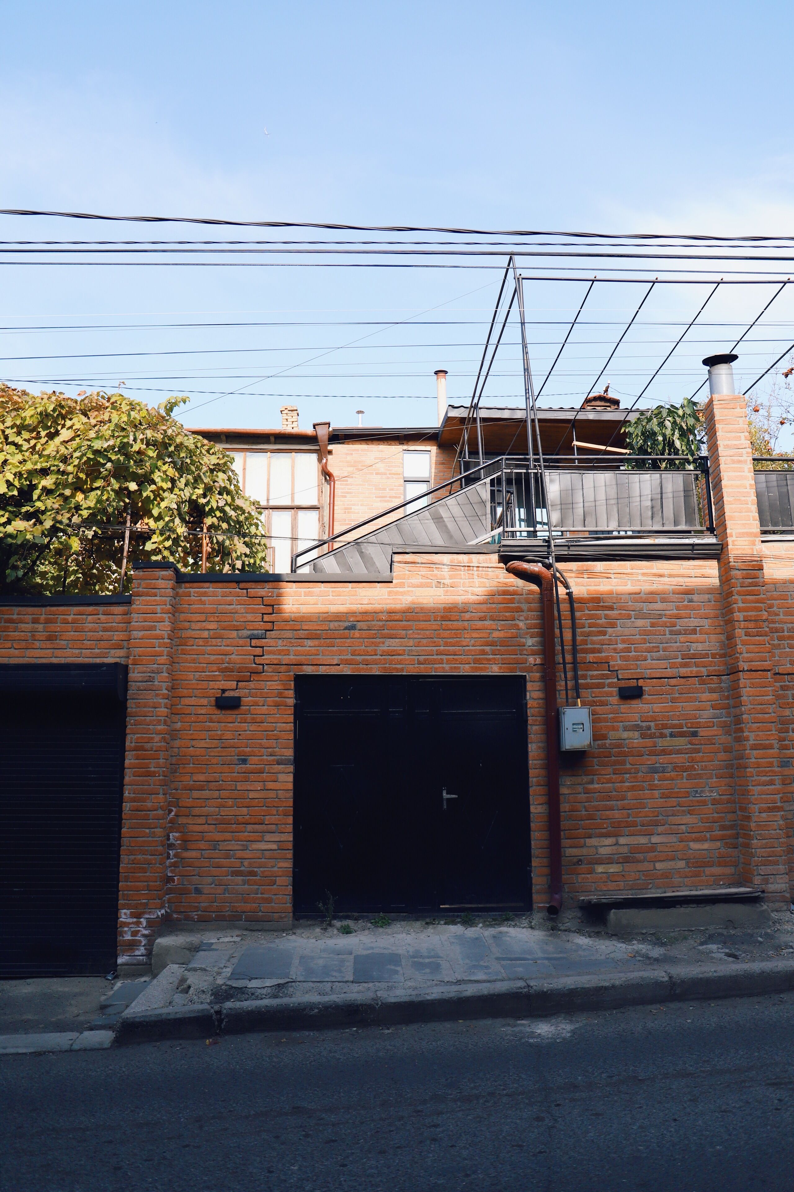 A brick building with two garage doors, a metal staircase, and a power line overhead.