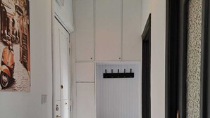 A hallway with a white door, a black door, a wall-mounted radiator, and a poster of a scooter. - La Mia Roma house-Charme Comfort & Relax-close subway-5 minutes from Colosseum (Roma)
