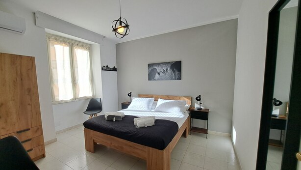 A bedroom with a wooden bed, a desk, a chair, a nightstand, a lamp, and a window with curtains. - La Mia Roma house-Charme Comfort & Relax-close subway-5 minutes from Colosseum (Roma)