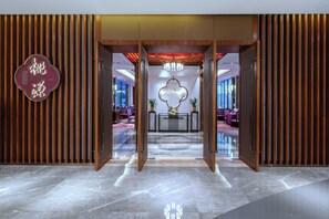 Eine moderne Hotellobby mit einer Rezeption, einer Kristallleuchter und einer Wandgestaltung aus Holz.