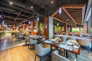 Un restaurant spacieux doté de plusieurs espaces de restauration, de touches de bois et d’un design moderne au niveau du plafond.