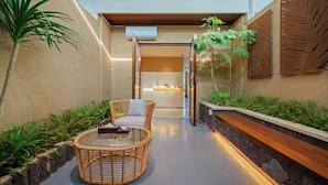 A modern indoor space with a glass-top table, wicker chairs, and a wooden bench. - Castfast Hotel (Dongguan)