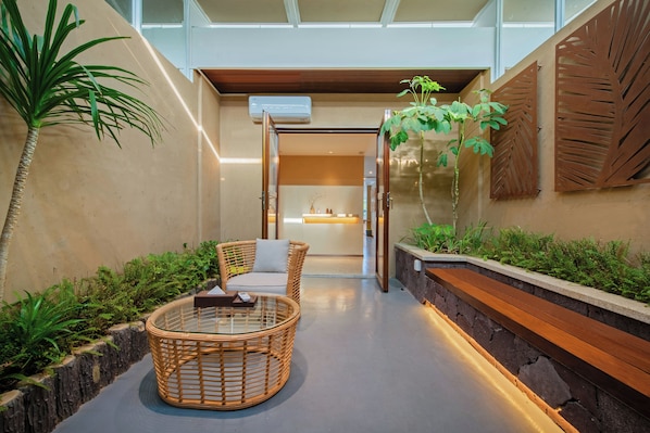A modern indoor space with a glass-top table, wicker chairs, and a wooden bench. - Castfast Hotel (Dongguan)