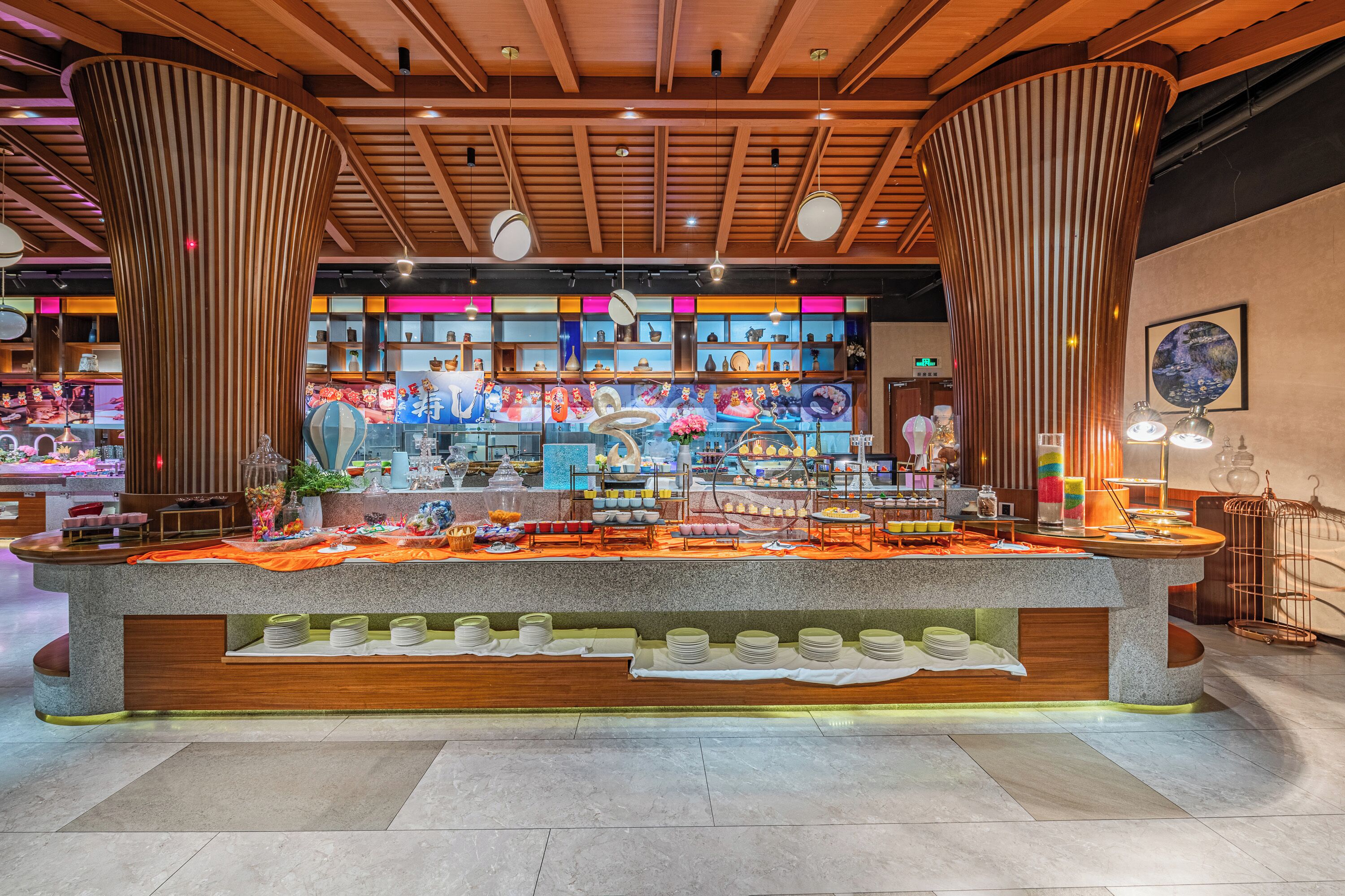 A buffet setup with a central island, surrounded by shelves with various food items and a large decorative column.