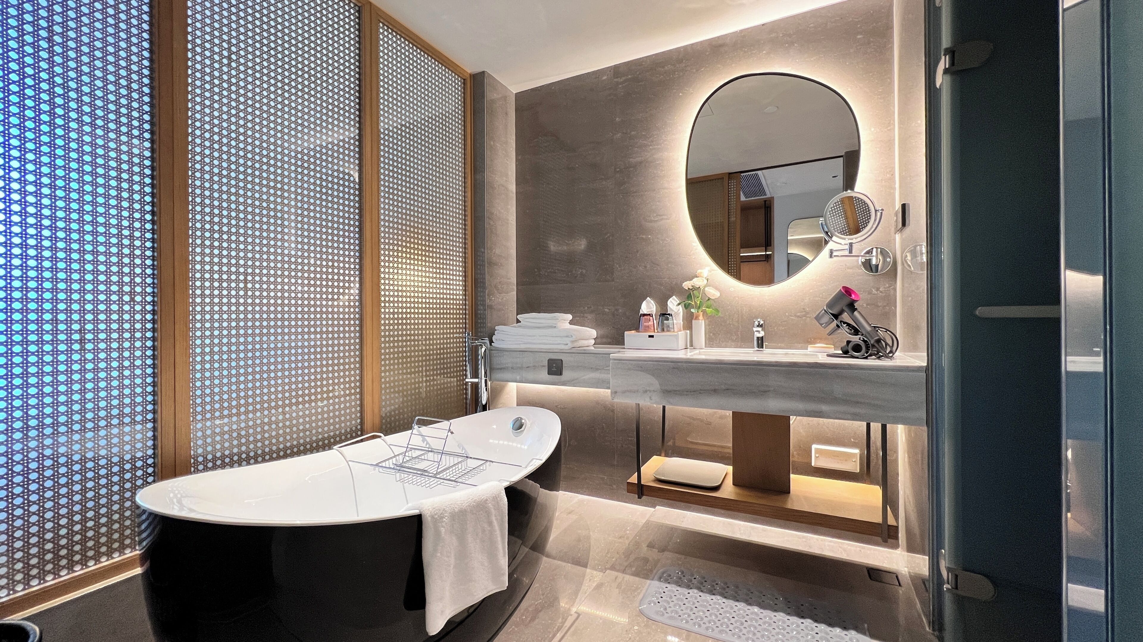 Ein modernes Badezimmer mit einer freistehenden Badewanne, einem großen Spiegel und einem Waschtisch mit zwei Becken.