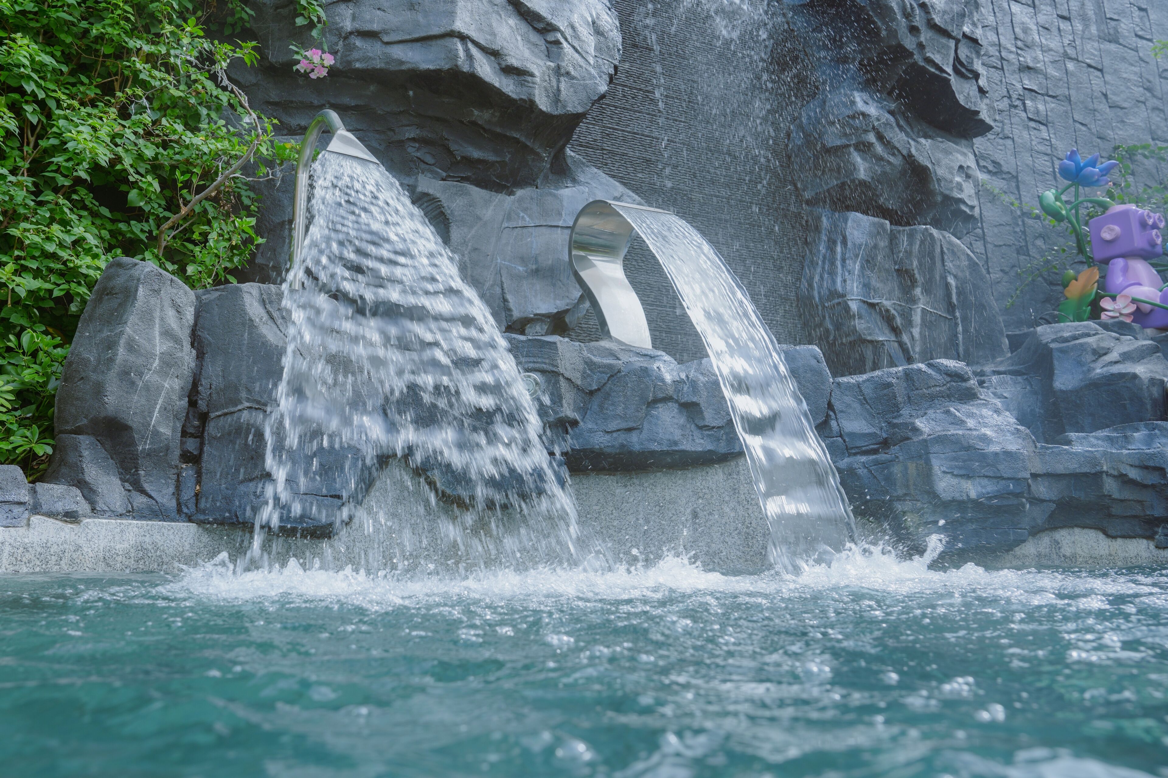 A waterfall feature with water cascading over rocks and a curved structure.