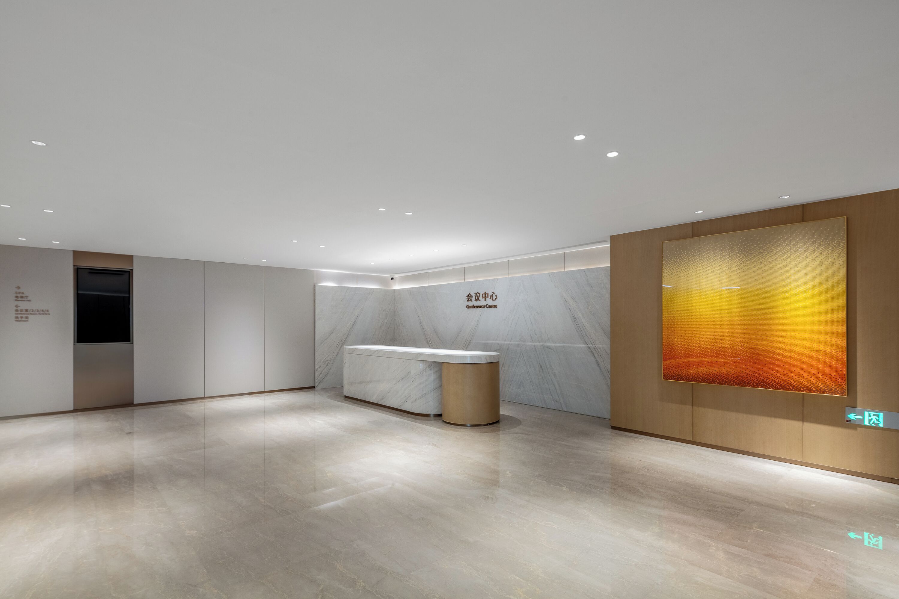 A reception area with a marble reception desk, a wall-mounted digital display, and a wooden panel with directional arrows.