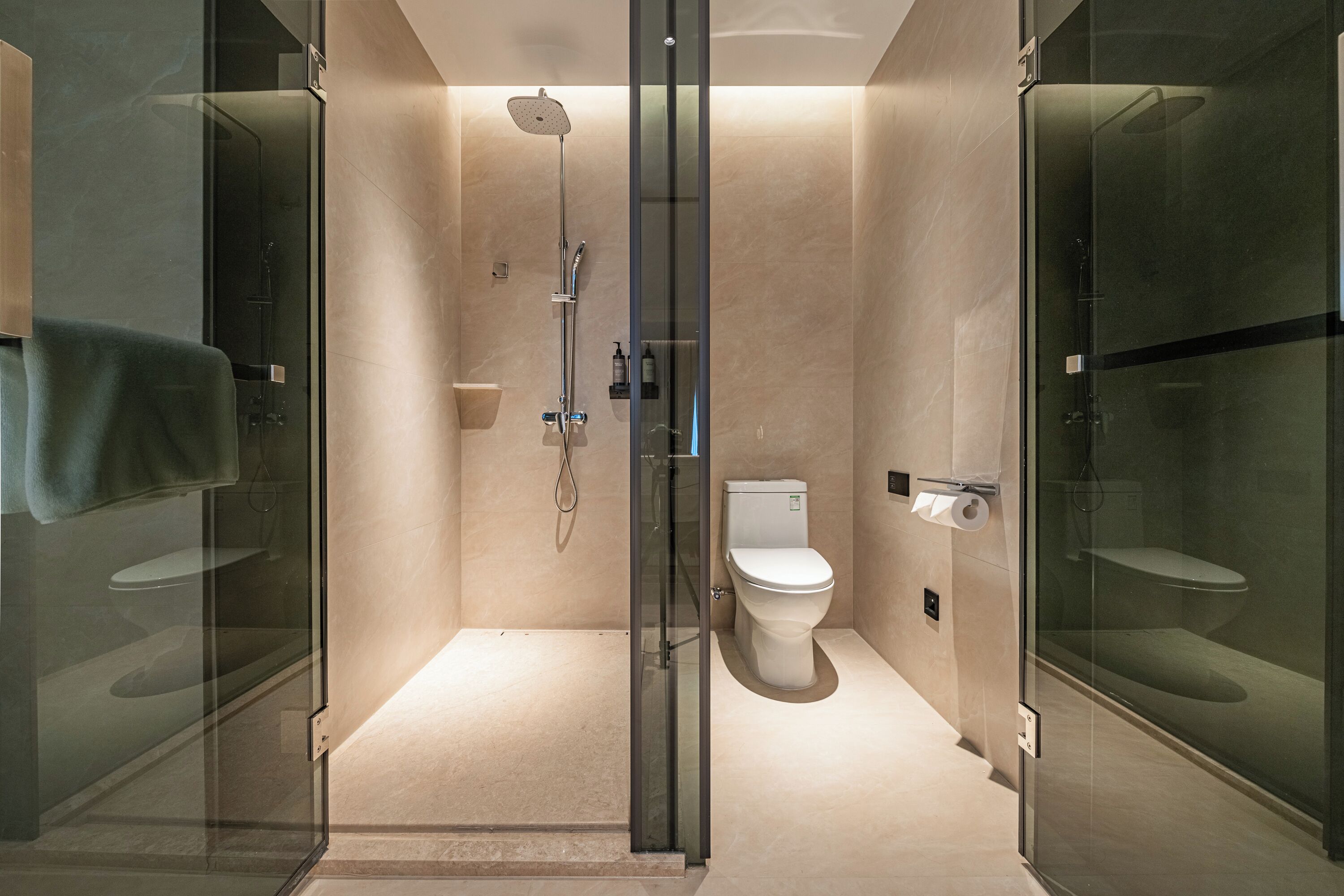 Un baño moderno con ducha acristalada, inodoro y puerta de vidrio.