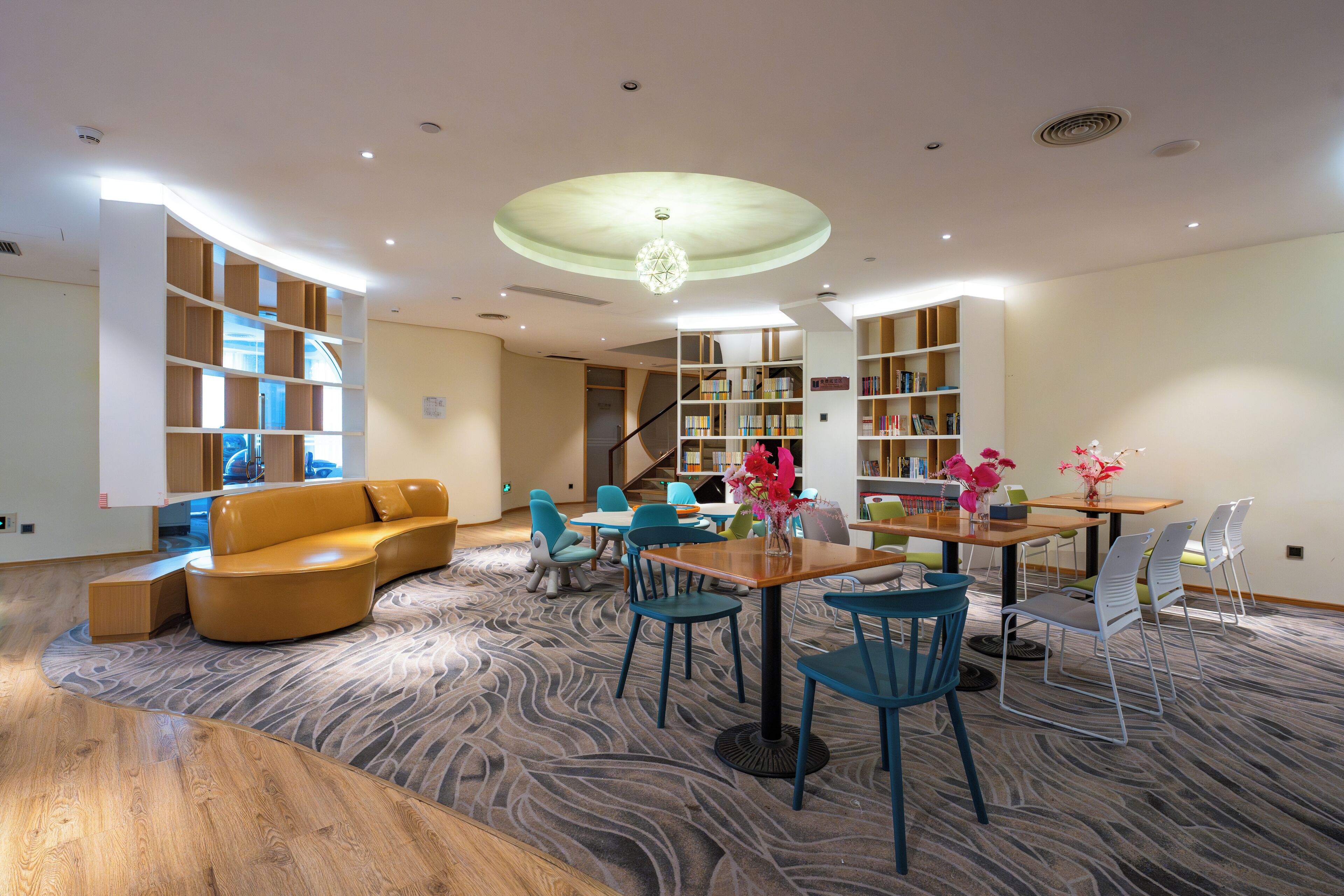 A modern interior with a curved sofa, a wooden coffee table, and a dining area with chairs and a table.