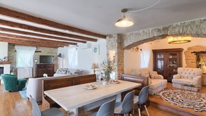 A spacious living area with a wooden dining table, modern chairs, and a stone fireplace. - Stancia Vigini by Villas Guide (Grožnjan)