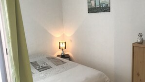 Een slaapkamer met een bed, een nachtkastje met een lamp, een houten kast en een schilderij aan de muur.