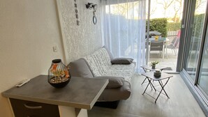 Een moderne woonkamer met een bank, een bijzettafeltje en een glazen deur die leidt naar een buitenruimte.