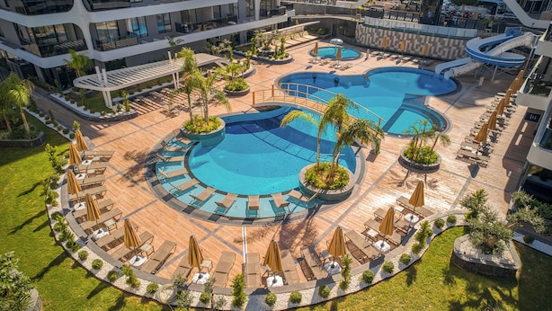 Un resort con varias piscinas, sillas de descanso y palmeras.