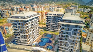 Un moderno complejo de apartamentos con varios balcones y un patio central con piscina.
