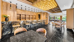 Un restaurante moderno con mostradores de mármol, paneles de madera y una araña. Mesas y sillas dispuestas para comer.