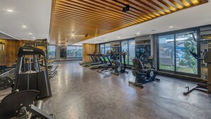 Un gimnasio moderno con máquinas de cardio, estaciones de pesas y amplios ventanales que ofrecen vistas al exterior.