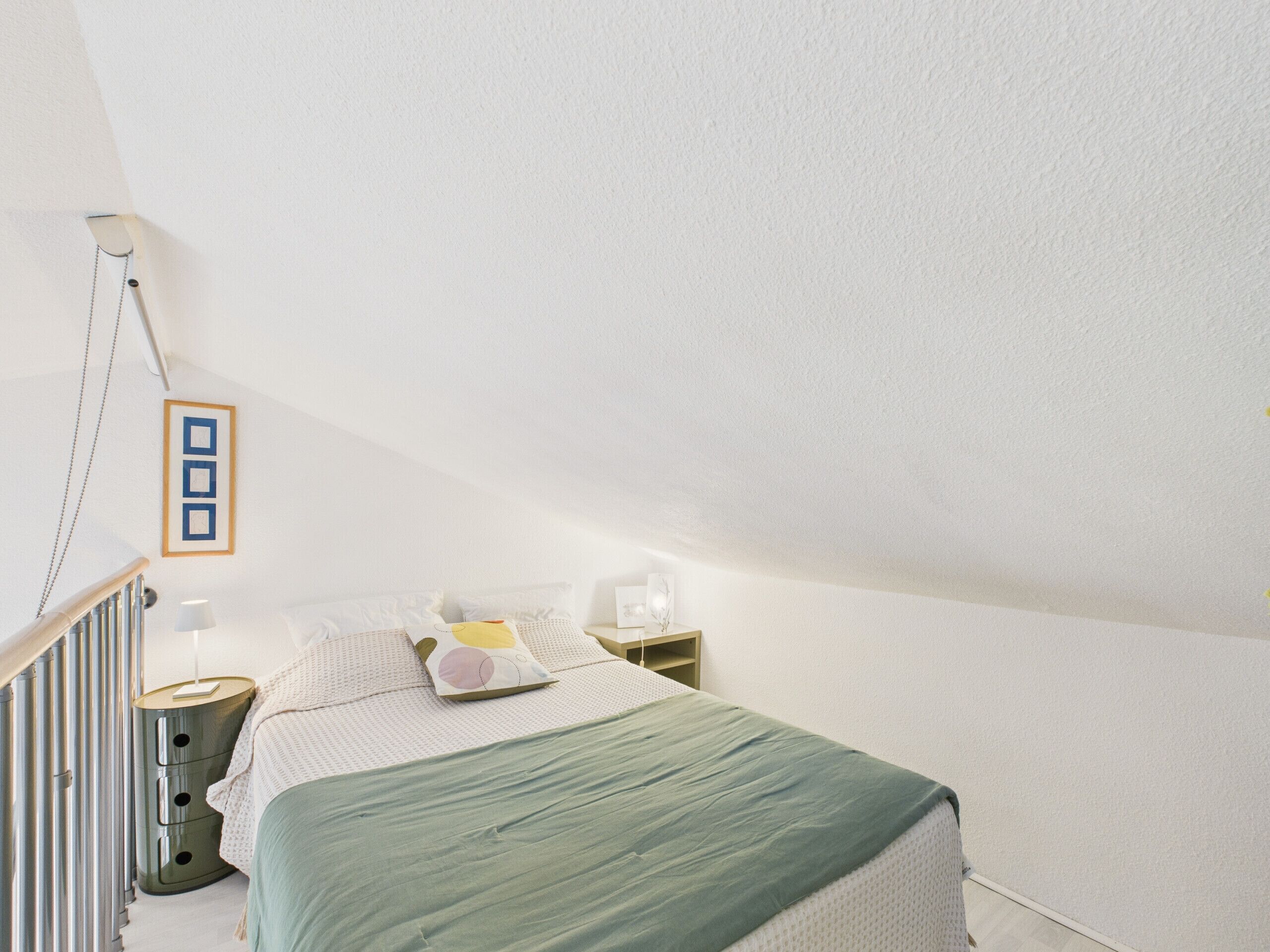 Une chambre à coucher avec un lit, des tables de chevet, une lampe et un tableau encadré au mur.