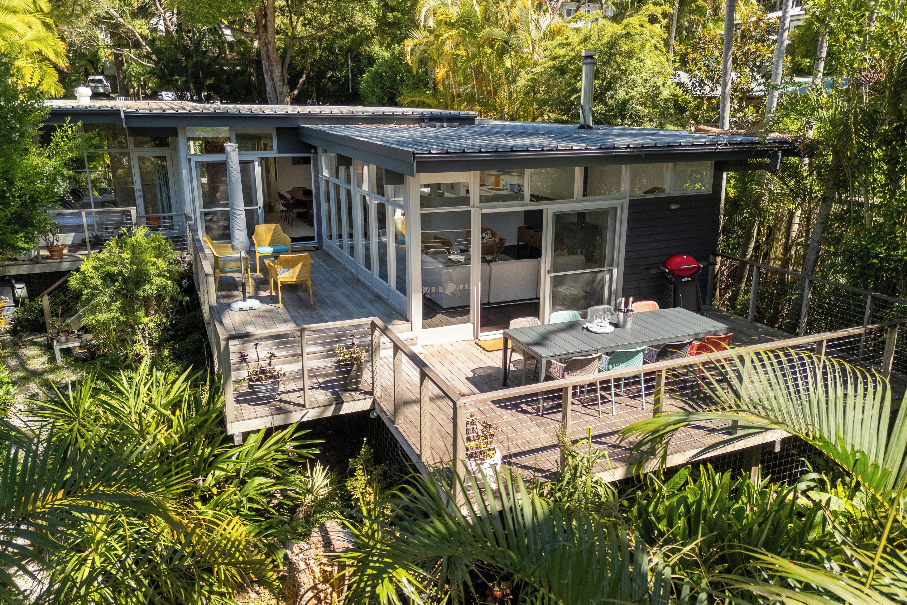 A modern house with a deck, large windows, and outdoor seating.
