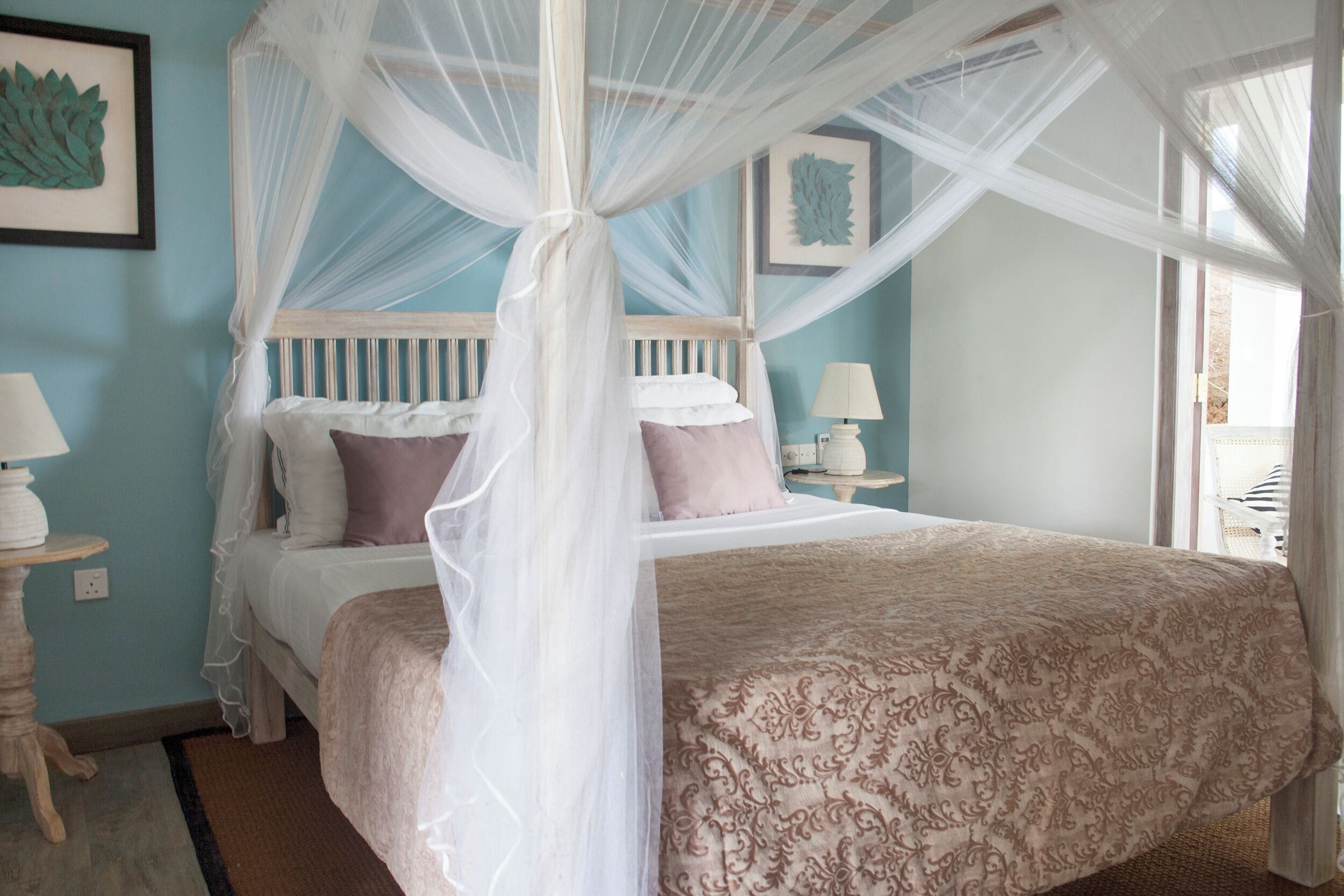 Quarto com cama de dossel, mesas de cabeceira e obras de arte nas paredes.