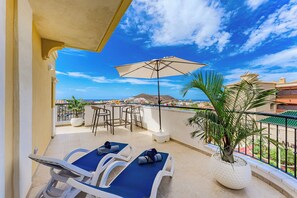 A balcony with two lounge chairs, a table, chairs, and a potted plant. - Apartment with an Ocean View and a Summery Atmosphere (Playa de las Américas)