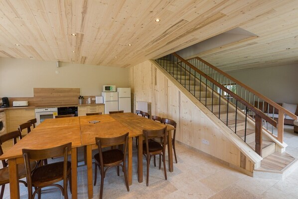Una cocina amplia con armarios de madera, una mesa de comedor y una escalera que sube a un nivel superior.