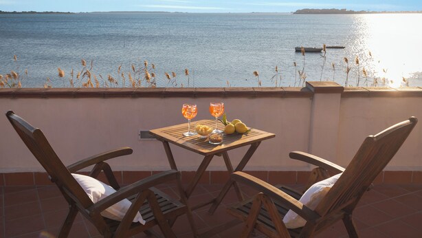 Een terras met twee houten stoelen en een tafel met drankjes en fruit.