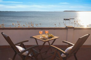 A terrace with two wooden chairs and a table with drinks and fruit. - Laguna dei Fenici (Marsala)