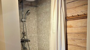 Un área de ducha con cabezal, ducha de mano y cortina.