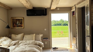 Un dormitorio con cama, mesita de noche, televisión y vistas a un paisaje verde.