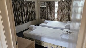 A room with two beds, a ceiling fan, and patterned curtains. - Cairns holiday unit apartment kitchen aircon wifi near esplanade and hospital (Cairns North)