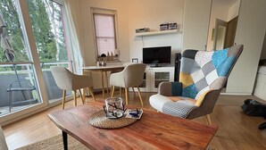 Un salon moderne avec une table basse en bois, un canapé coloré et un téléviseur.