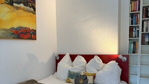 Une chambre à coucher avec un lit, une bibliothèque et un tableau accroché au mur.