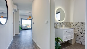 Un bagno moderno con uno specchio rotondo, un mobile lavabo bianco e pavimento in terrazzo.